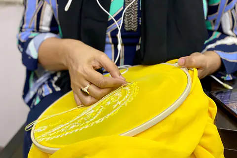 Ricamo a mano su un capo giallo nel telaio