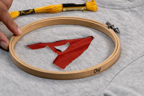 Ricamo di una lettera su una maglietta con telaio in legno